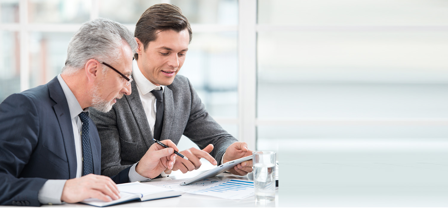 Due uomini d'affari commentano informazioni di fronte a un tablet.