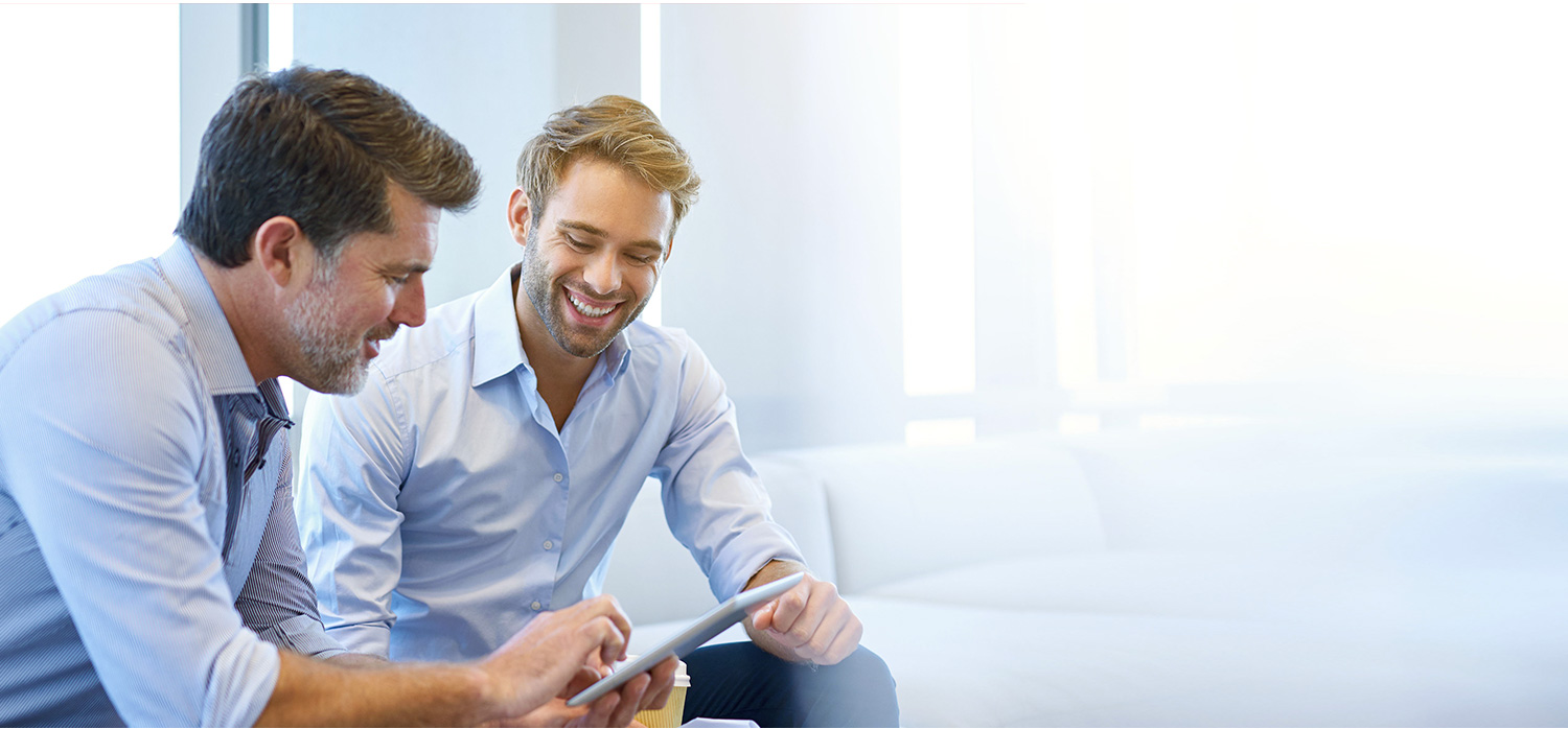 Due professionisti di età diverse in camicia condividono e commentano informazioni sul tablet. 