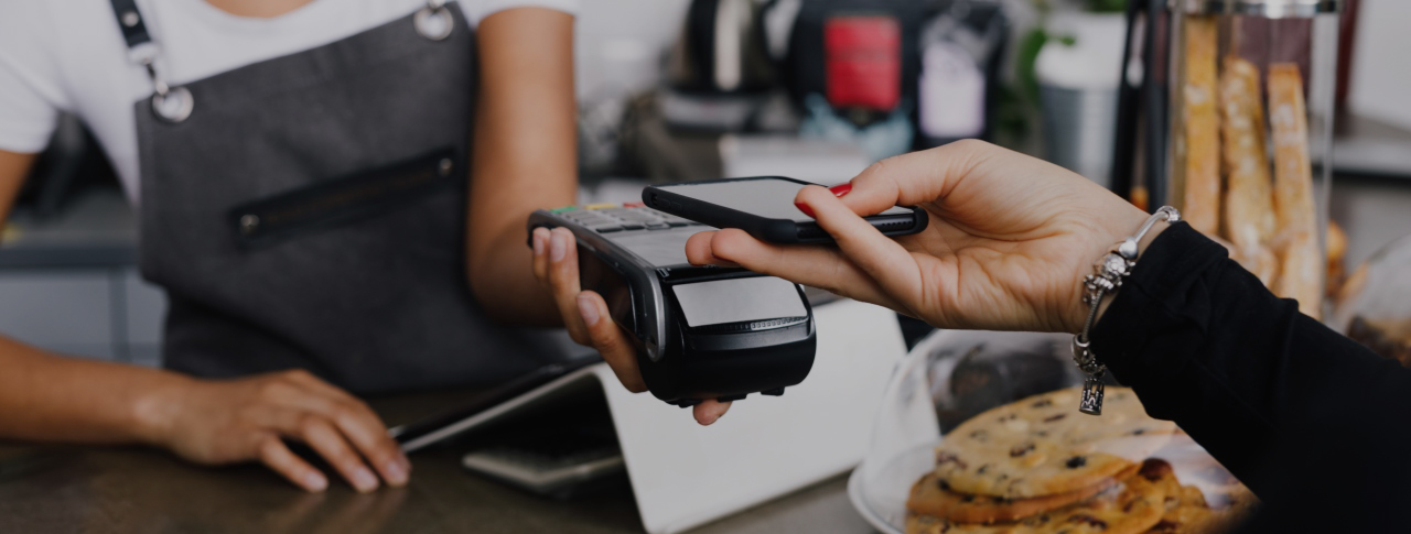 Giovane donna paga in un caffè con il proprio smartphone.