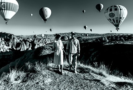 Una coppia passeggia sotto le mongolfiere della Cappadocia.