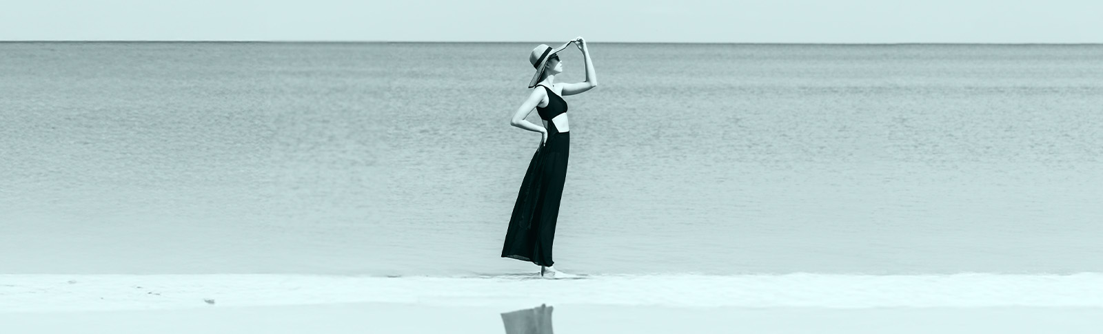 Ragazza con il cappello guarda il mare.